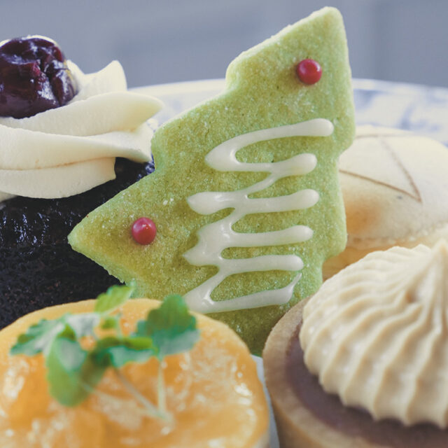 Christmas afternoon tea treats, including a shortbread biscuit decorated as a Christmas tree, a mini Black forest Gateau cake, a cinnamon and apple tart and a lemon cheesecake